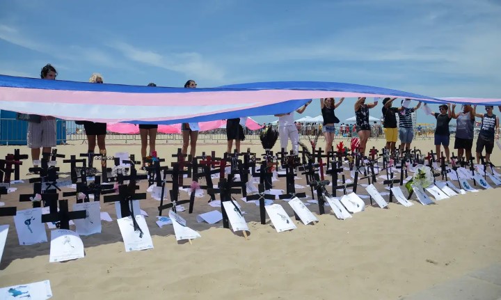 manifestação de pessoas trans segurando bandeira