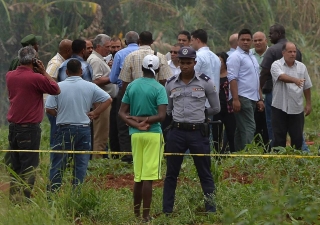 Policial guarda perÃmetro isolado do público enquanto, ao fundo, o presidente de Cuba, Miguel Diaz-Canel, conversa com um grupo após chegar ao local do acidente aéreo em Havana (Foto: Yamil Lage/AFP) Policial guarda perÃmetro isolado do público enquanto, ao fundo, o presidente de Cuba, Miguel Diaz-Canel, conversa com um grupo após chegar ao local do acidente aéreo em Havana (Foto: Yamil Lage/AFP)